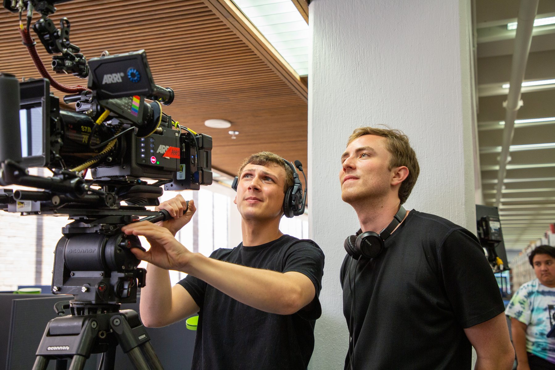 Eric operates a cinema camera during an indoor production setup.